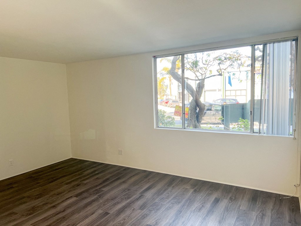 an empty living room with a large window and wooden floors