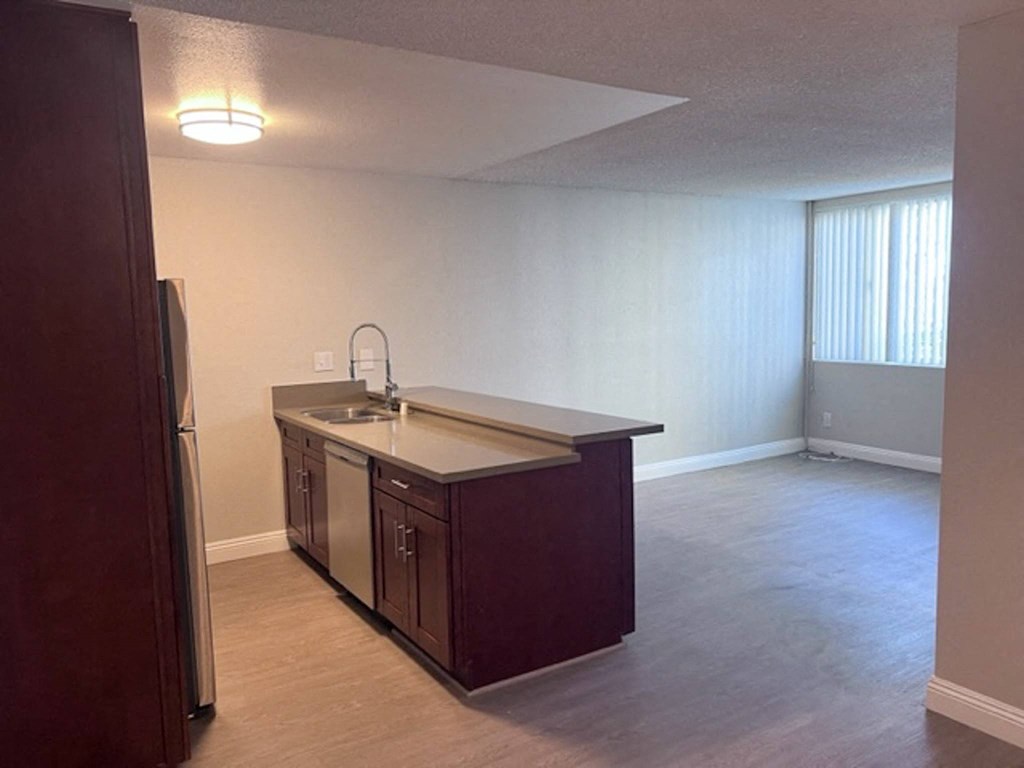 an empty kitchen and living room with a refrigerator and sink