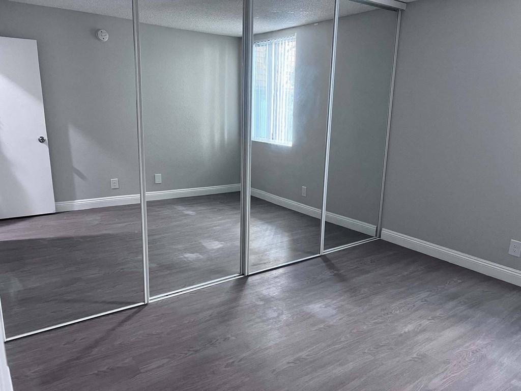 a bedroom with mirrored closet doors and a window