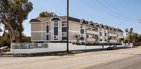 A row of townhouses with a white fence in front.