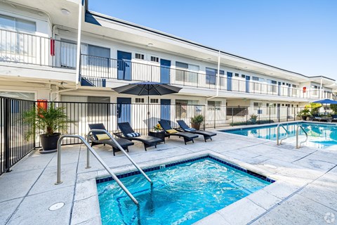 A pool area with a small pool and lounge chairs.