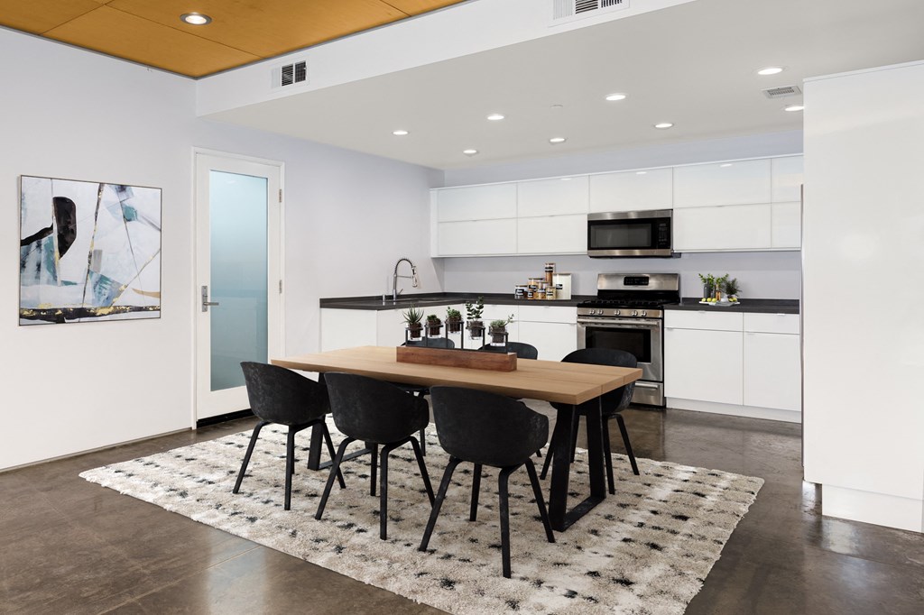 a kitchen with white cabinets and a table with black chairs