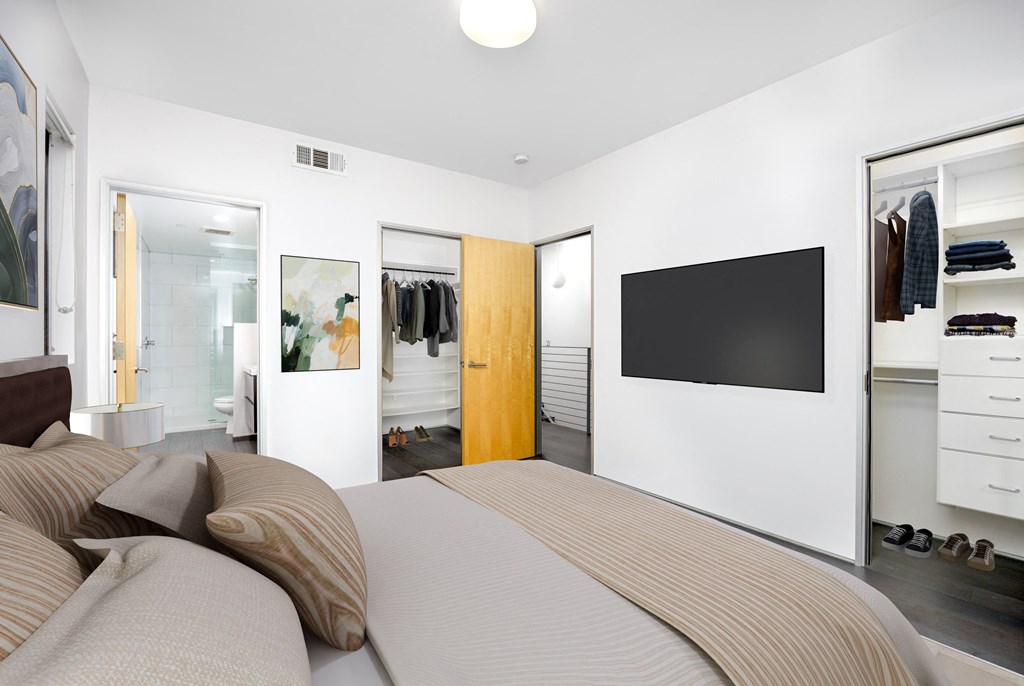 a bedroom with a large bed and a bathroom with a tv