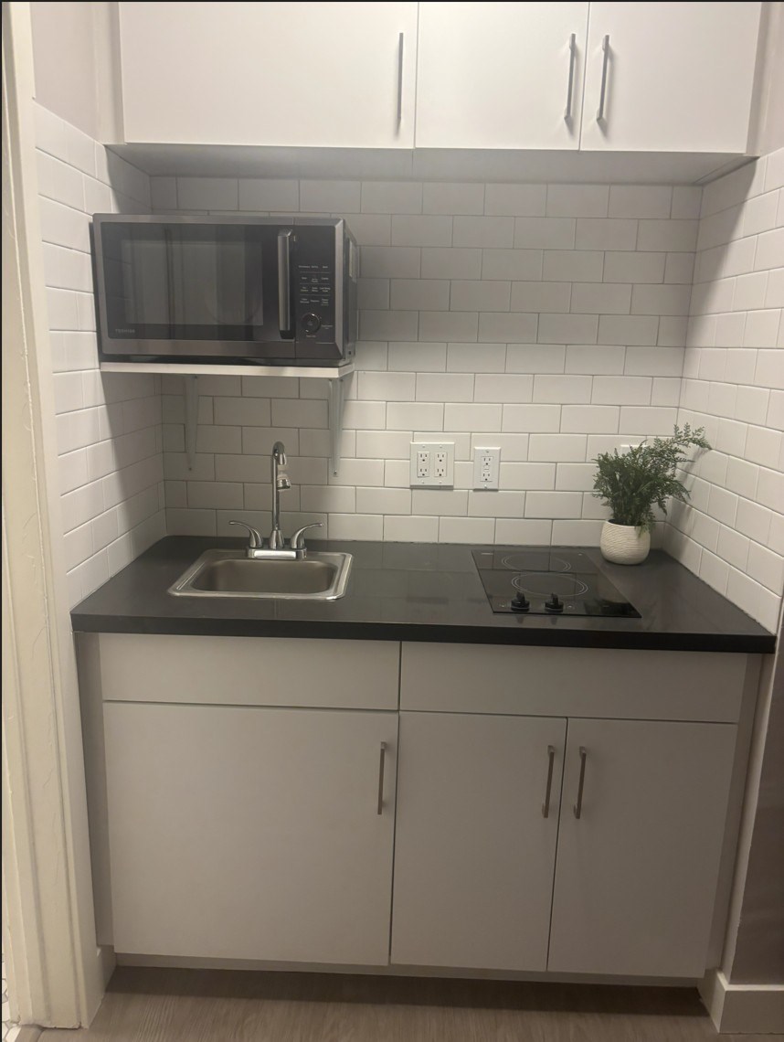 A kitchen with a black countertop and white cabinets.