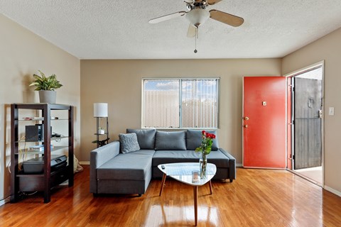 A living room with a grey couch, a white coffee table, and a red door.