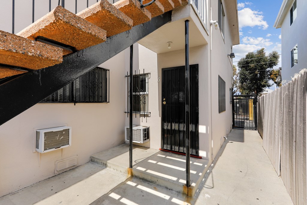 A white house with a black gate and a red brick wall.