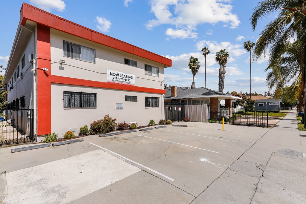 A building with a red and white facade has a sign that says "NOW LEASING ZIP 90077-7807".
