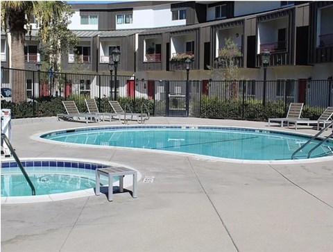 A pool with a bench and chairs in front of a building.