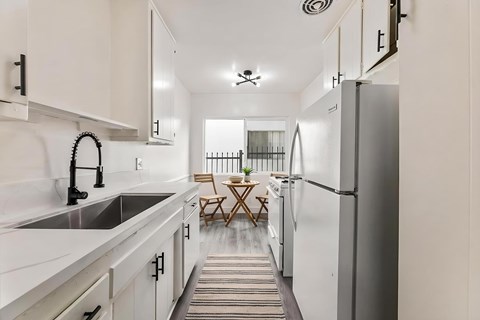 A kitchen with white cabinets and a striped rug on the floor.