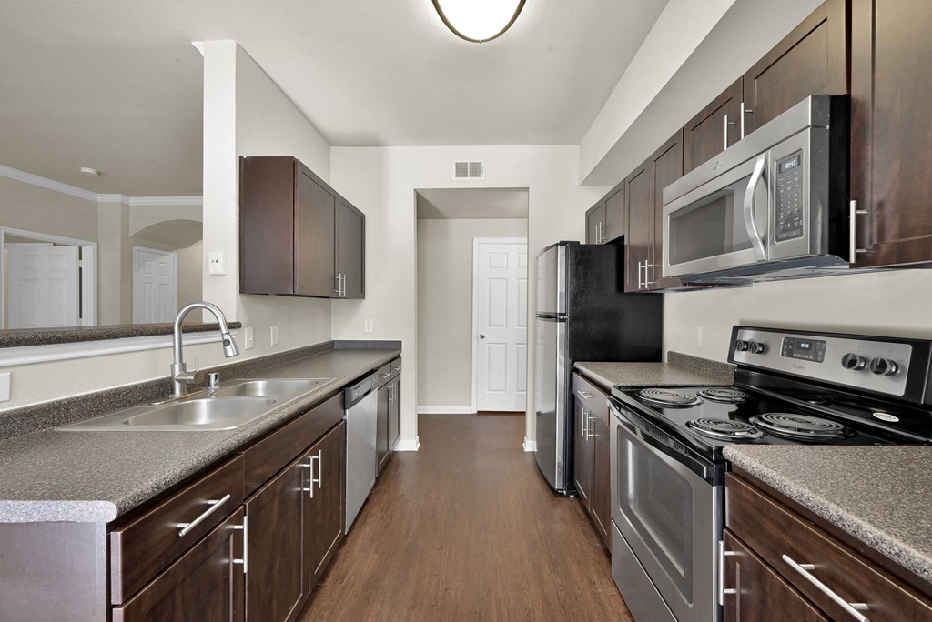 a kitchen with dark wood cabinets and stainless steel appliances