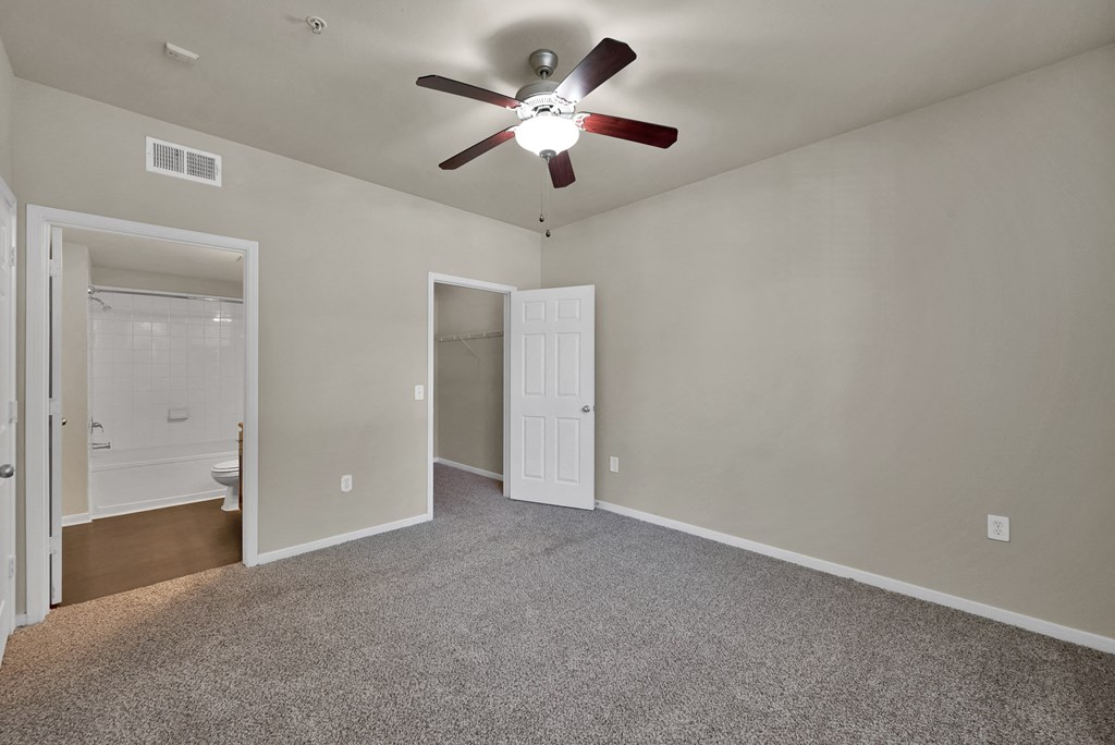 a bedroom with a ceiling fan and a door to a bathroom