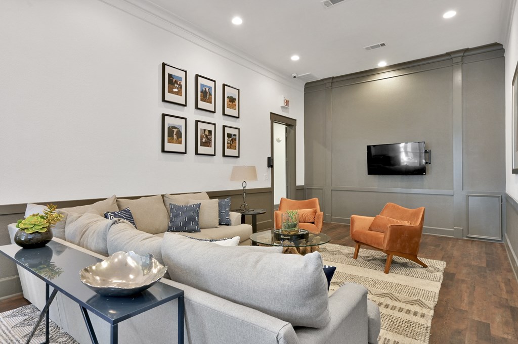 a living room with a gray couch and a tv on the wall