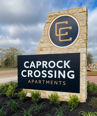 a sign for caprock crossing apartments in front of a parking lot