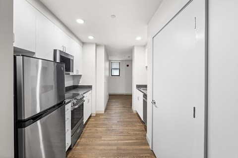 a long white kitchen with stainless steel appliances and white cabinets