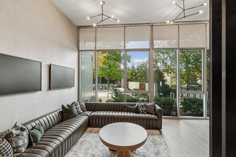 A modern living room with a large window and a brown sofa.