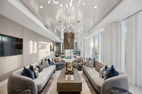 A modern living room with grey couches and a chandelier.