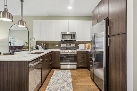 A modern kitchen with a refrigerator on the right and a stove top oven in the middle.