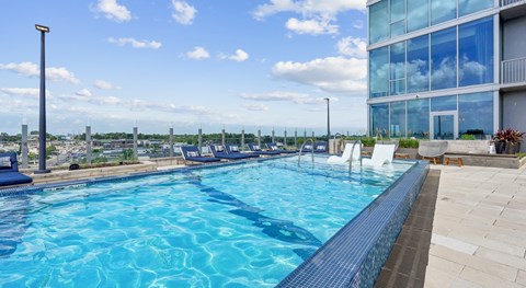 A large swimming pool with a blue tiled edge and a white chair on the right side.
