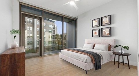 A bedroom with a large bed and a view of a building outside the window.