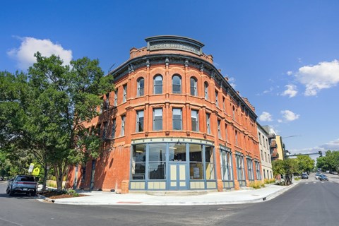 A large red building with a curved corner and a black car parked in front.