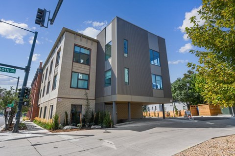 A modern building with a glass facade is situated on a street corner.