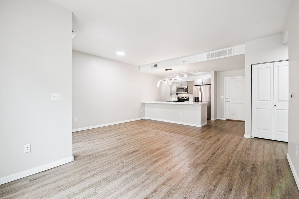A large empty room with wooden flooring and white walls.