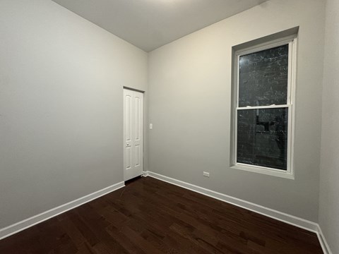 A room with a white door and a window with a view of a building outside.
