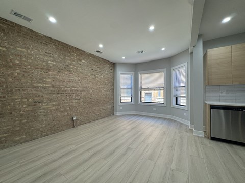 A kitchen with a brick wall and wooden floors.