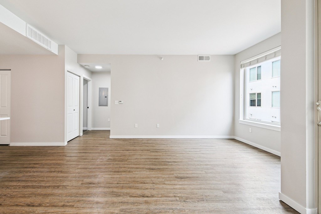 A spacious room with wooden flooring and white walls.