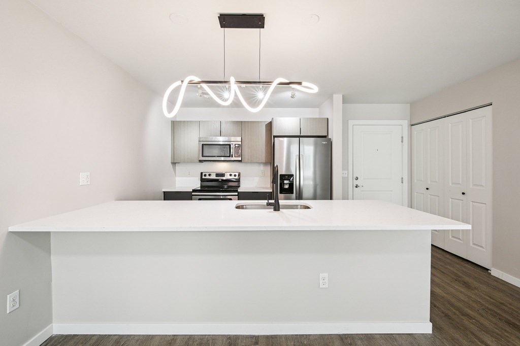 A modern kitchen with a white island and a white fridge.
