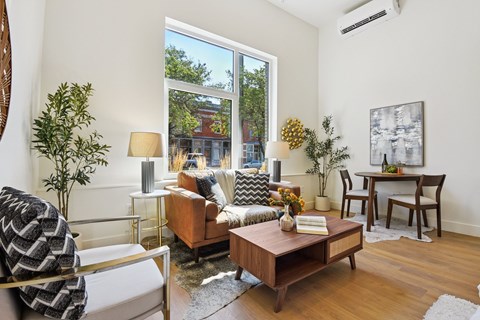 A living room with a brown sofa, a wooden coffee table, and a painting on the wall.