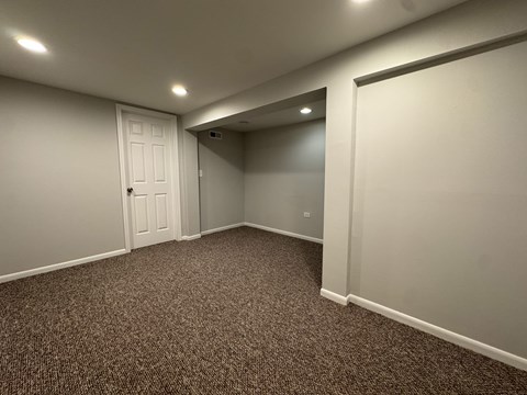 A room with a carpeted floor and a white door.