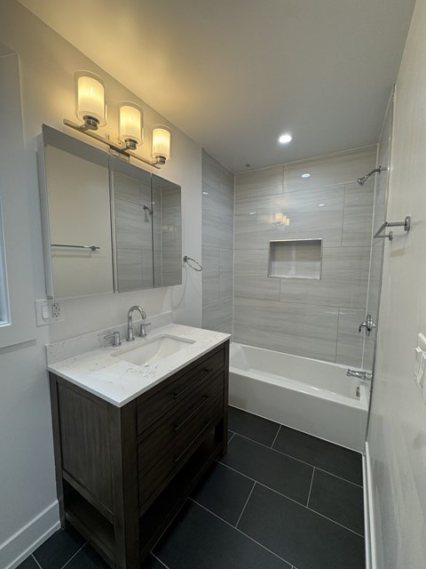 A modern bathroom with a white sink and a black tile floor.
