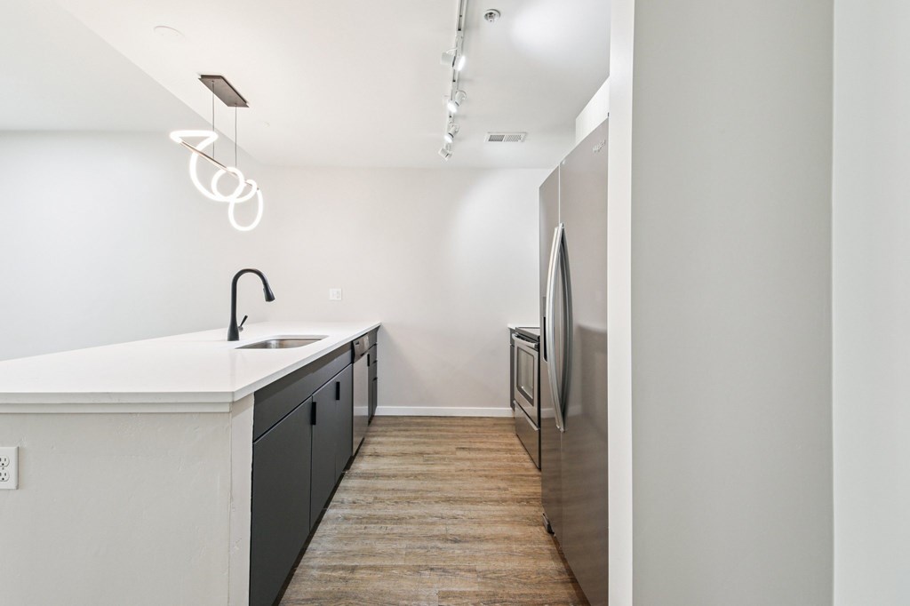 A modern kitchen with a white countertop and dark cabinets.