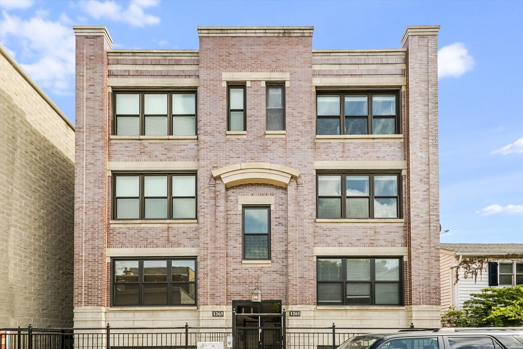 A red brick building with a black gate in front.