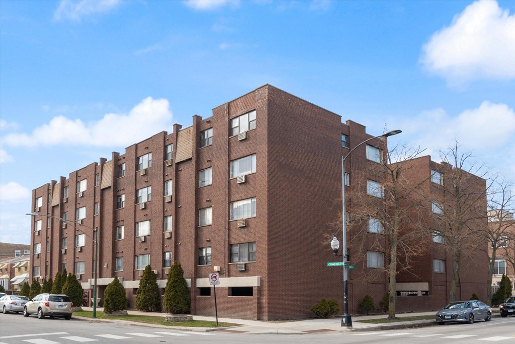 a red brick apartment building with cars parked in front of it
