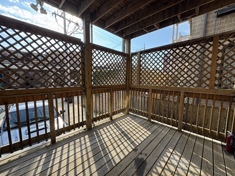 A wooden deck with lattice work and a car parked in the background.
