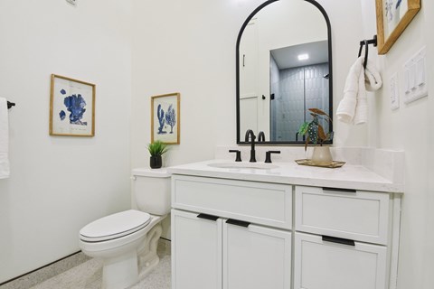 A white bathroom with a toilet, sink, and mirror.