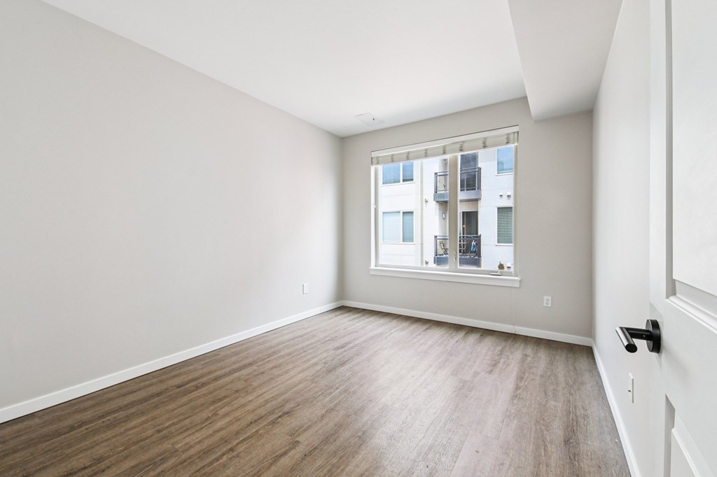 A room with a window and wooden flooring.
