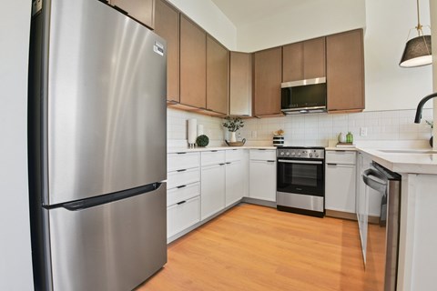A modern kitchen with a stainless steel refrigerator and wooden cabinets.