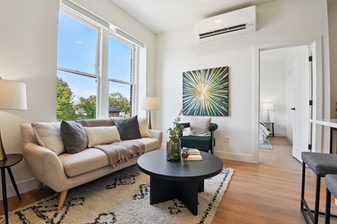 A living room with a couch, a coffee table, and a painting on the wall.