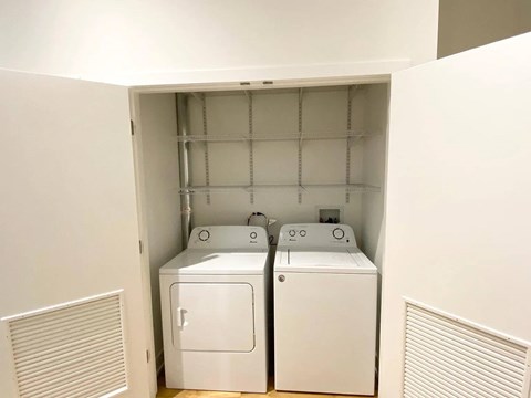 Two white washing machines in a small laundry room.