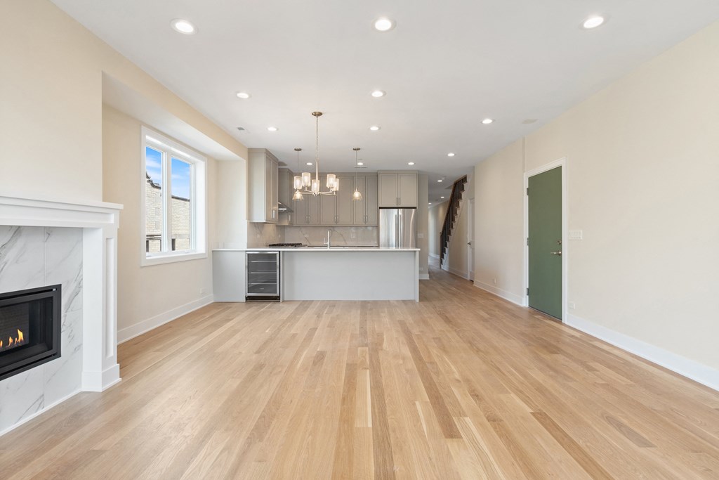 an empty living room with a fireplace and a kitchen