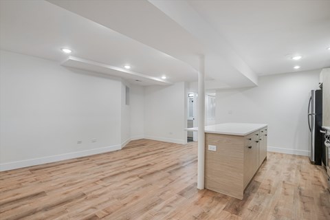 A spacious room with wooden flooring and white walls.