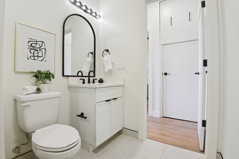 A white bathroom with a toilet, sink, and mirror.
