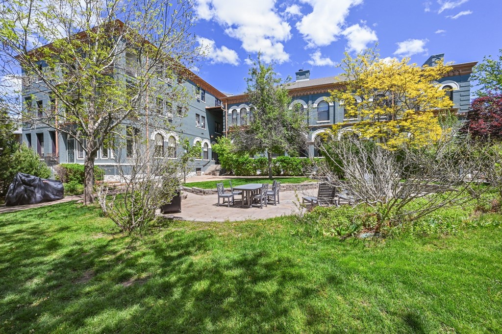 a backyard with a table and chairs in front of a house