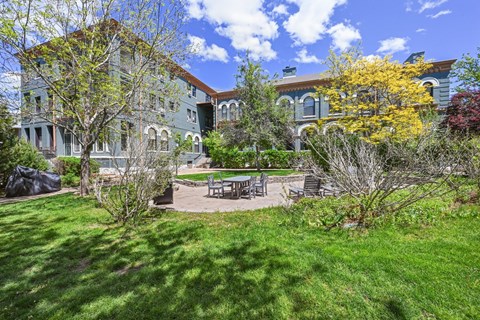 a backyard with a table and chairs in front of a house