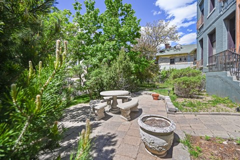 a patio with a table and benches in front of a building