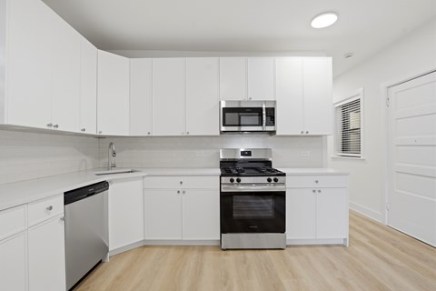 A modern kitchen with white cabinets and stainless steel appliances.