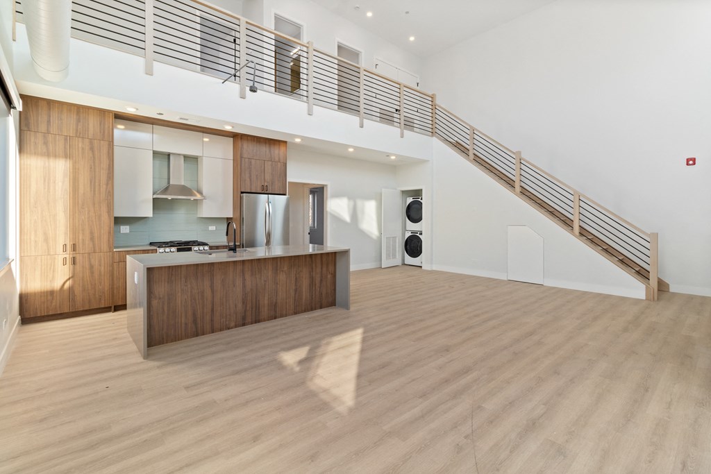 a large living room with a kitchen and a staircase